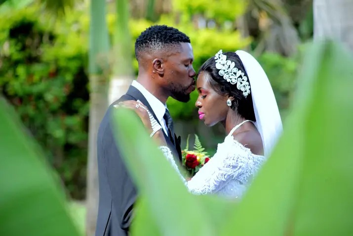 Couple kissing framed by foliage